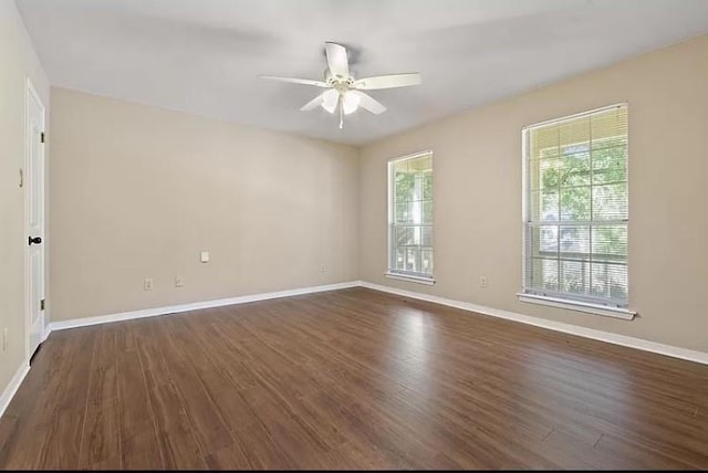 unfurnished room with ceiling fan, plenty of natural light, and dark wood-type flooring