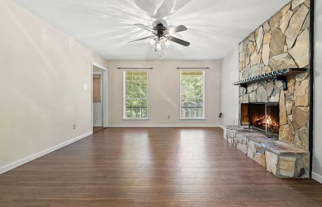 unfurnished living room featuring a textured ceiling, ceiling fan, a fireplace, and dark wood-type flooring