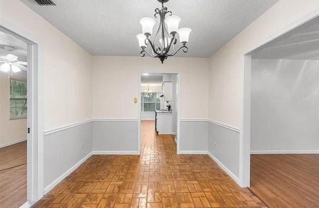 unfurnished dining area with a textured ceiling and a notable chandelier