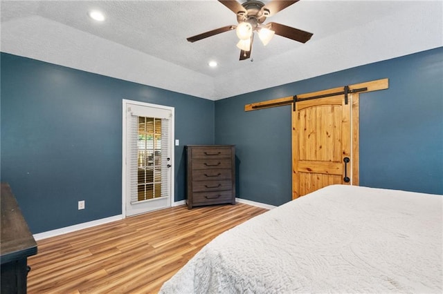 3420 Floyd Cir E, Semmes, AL 36575 - bedroom with wood finished floors, a barn door, a textured ceiling, a ceiling fan, and recessed lighting