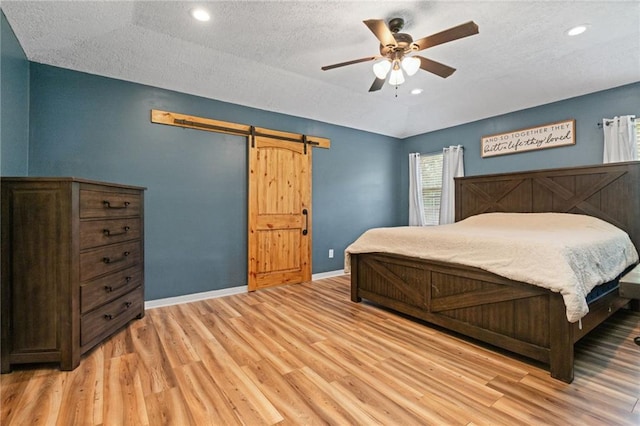 3420 Floyd Cir E, Semmes, AL 36575 - bedroom featuring a barn door, light wood-type flooring, a textured ceiling, ceiling fan, and recessed lighting