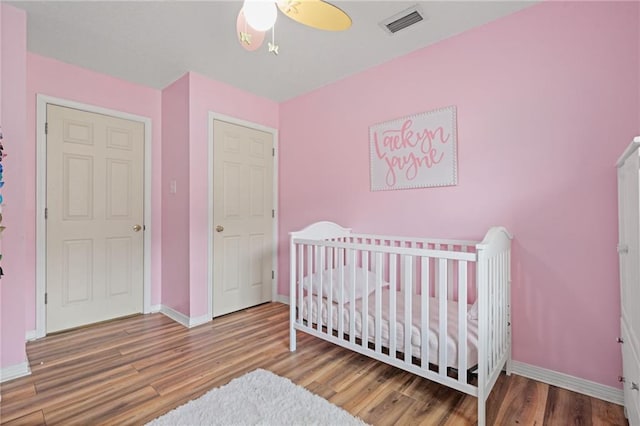 3420 Floyd Cir E, Semmes, AL 36575 - bedroom featuring wood finished floors, a crib, and a ceiling fan