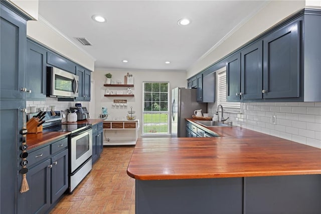3420 Floyd Cir E, Semmes, AL 36575 - kitchen featuring appliances with stainless steel finishes, wooden counters, brick flooring, decorative backsplash, and ornamental molding