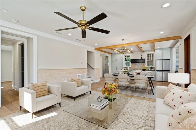 living room with light hardwood / wood-style flooring, ceiling fan with notable chandelier, and crown molding