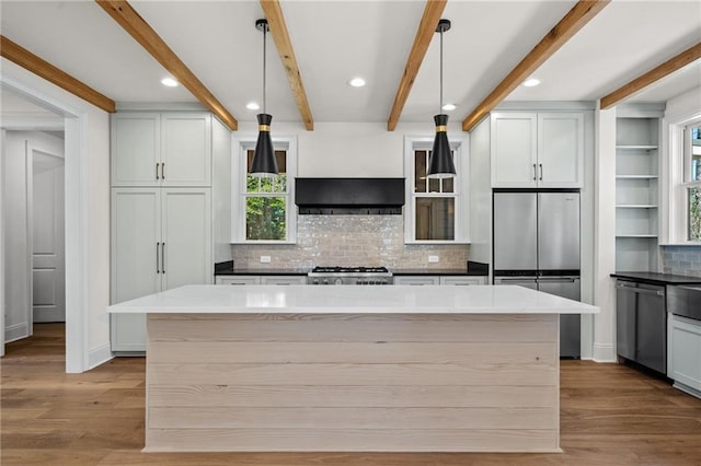 kitchen featuring a kitchen island, wood finished floors, stainless steel appliances, and beamed ceiling