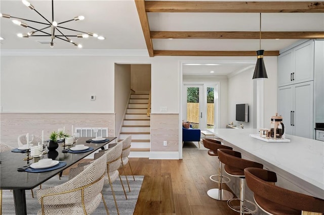 kitchen with crown molding, beamed ceiling, hardwood / wood-style flooring, light stone countertops, and pendant lighting