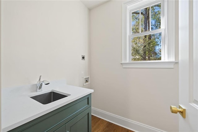 laundry area featuring dark wood-style flooring, baseboards, a sink, hookup for an electric dryer, and cabinet space