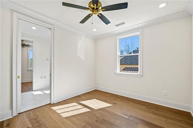 unfurnished bedroom with baseboards, visible vents, multiple windows, and wood finished floors