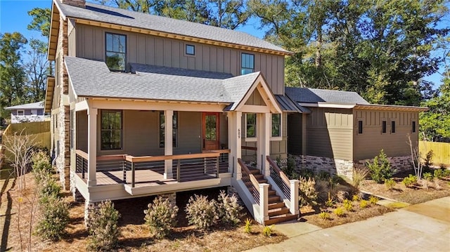 view of front of property with a shingled roof, covered porch, stone siding, and board and batten siding