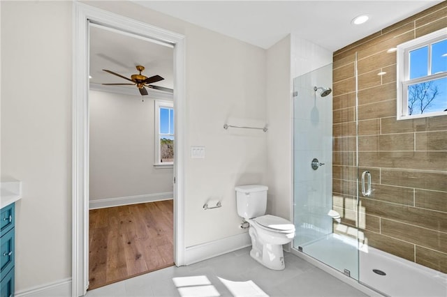 bathroom with toilet, baseboards, tile patterned floors, a stall shower, and a ceiling fan
