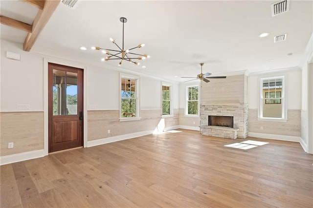 unfurnished living room featuring ceiling fan with notable chandelier, light wood-type flooring, a fireplace, and ornamental molding