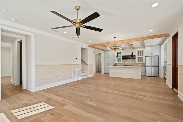 unfurnished living room featuring ceiling fan with notable chandelier and light hardwood / wood-style floors