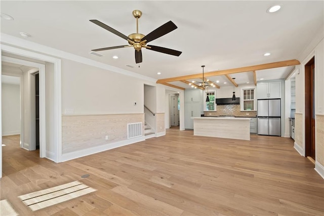 unfurnished living room featuring stairs, visible vents, light wood-style floors, and ceiling fan with notable chandelier