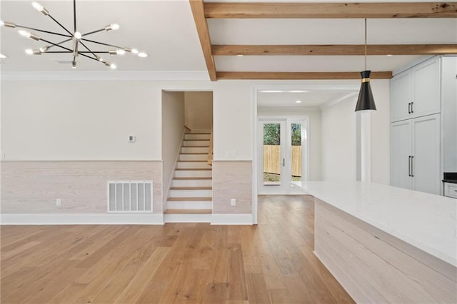 unfurnished living room with light wood-style flooring, visible vents, a chandelier, stairway, and beam ceiling