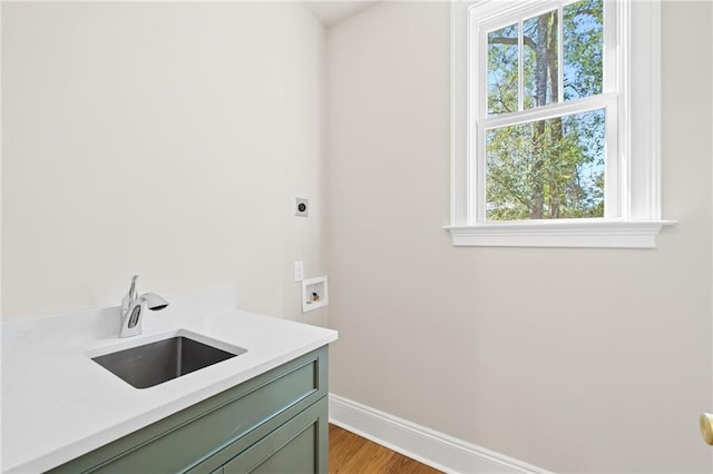 washroom featuring baseboards, a sink, light wood-style floors, cabinet space, and electric dryer hookup