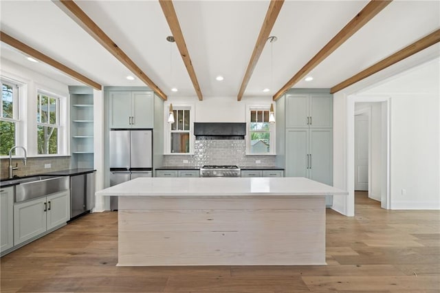 kitchen with decorative backsplash, light wood-type flooring, beam ceiling, and decorative light fixtures