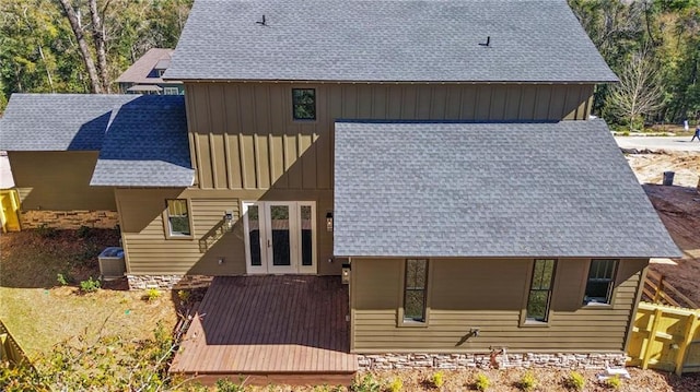 rear view of house featuring french doors, board and batten siding, stone siding, and roof with shingles