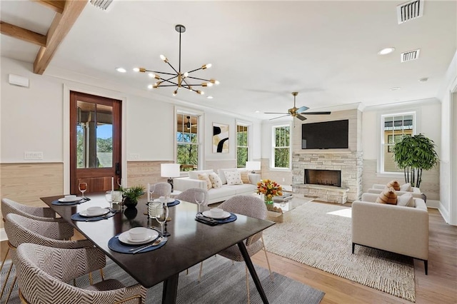 living room featuring ceiling fan with notable chandelier, a fireplace, crown molding, and light hardwood / wood-style flooring