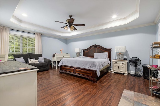 bedroom with ornamental molding, dark wood-type flooring, ceiling fan, and a tray ceiling