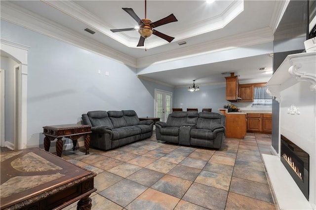 tiled living room with crown molding, ceiling fan, and a raised ceiling