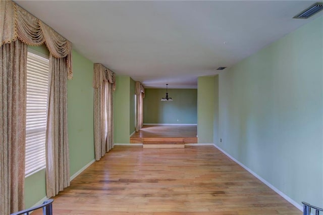 spare room featuring light hardwood / wood-style flooring and an inviting chandelier