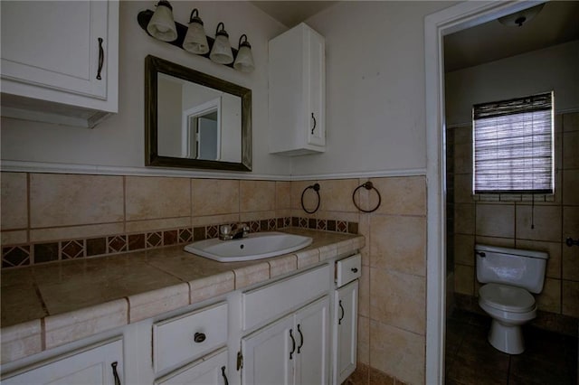 bathroom with tile patterned flooring, vanity, toilet, and tile walls