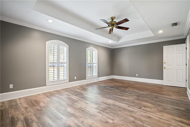 spare room with ceiling fan, crown molding, hardwood / wood-style floors, a textured ceiling, and a tray ceiling