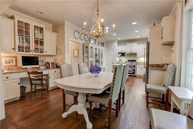 dining room featuring dark wood-type flooring, built in desk, a chandelier, and crown molding