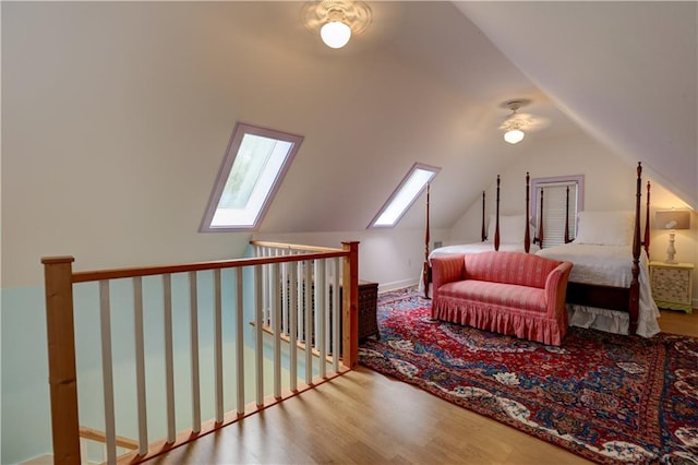 bedroom with ceiling fan, hardwood / wood-style flooring, and lofted ceiling with skylight