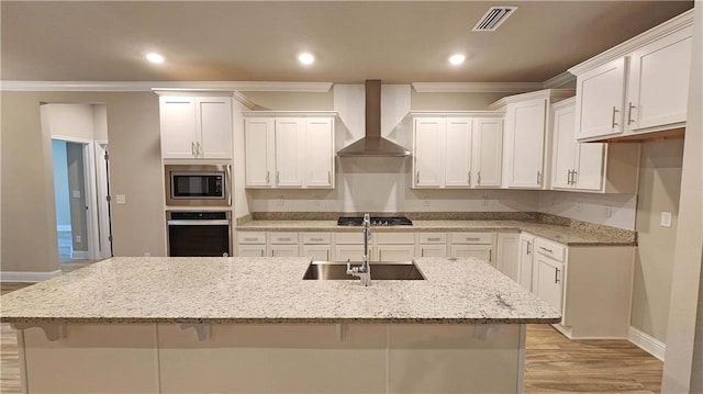 kitchen with a breakfast bar, sink, wall chimney exhaust hood, appliances with stainless steel finishes, and white cabinetry