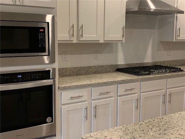 kitchen with white cabinetry, wall chimney range hood, and stainless steel appliances