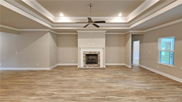 unfurnished living room featuring ceiling fan, ornamental molding, a fireplace, and a tray ceiling