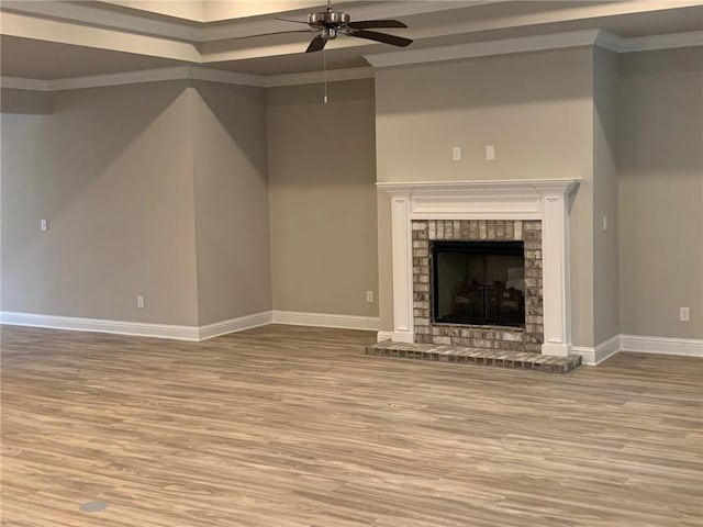 unfurnished living room featuring hardwood / wood-style flooring, ceiling fan, a fireplace, and crown molding