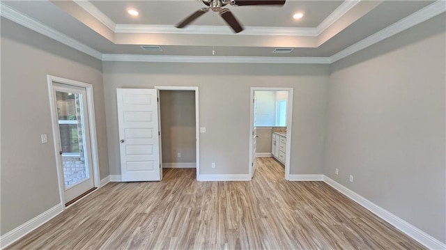 unfurnished bedroom featuring a tray ceiling, ceiling fan, ornamental molding, and light wood-type flooring