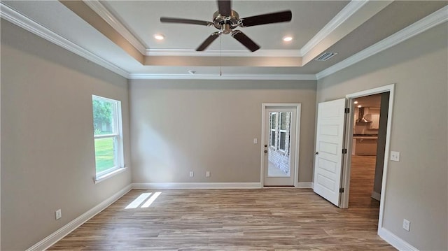 interior space with a tray ceiling, crown molding, ceiling fan, and light hardwood / wood-style floors