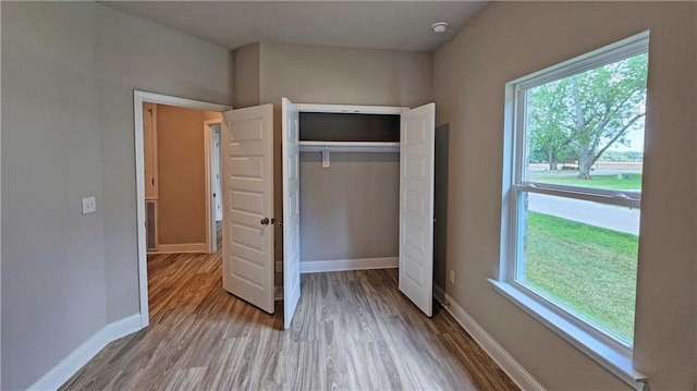 unfurnished bedroom featuring multiple windows, a closet, and light hardwood / wood-style floors