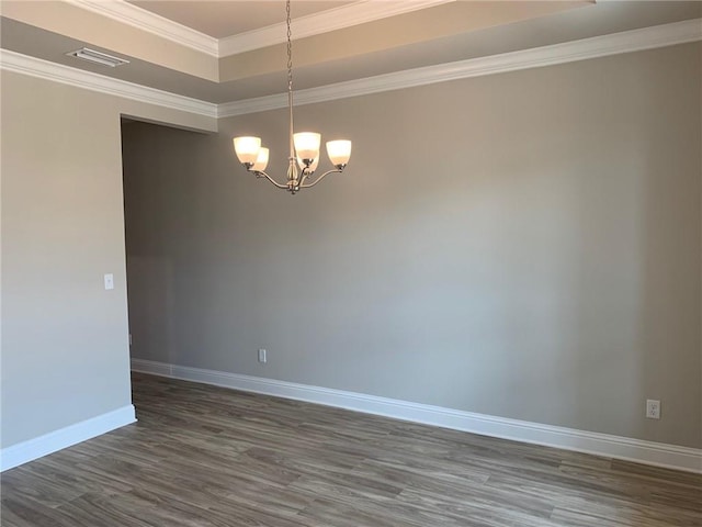 empty room with a notable chandelier, dark hardwood / wood-style floors, crown molding, and a tray ceiling