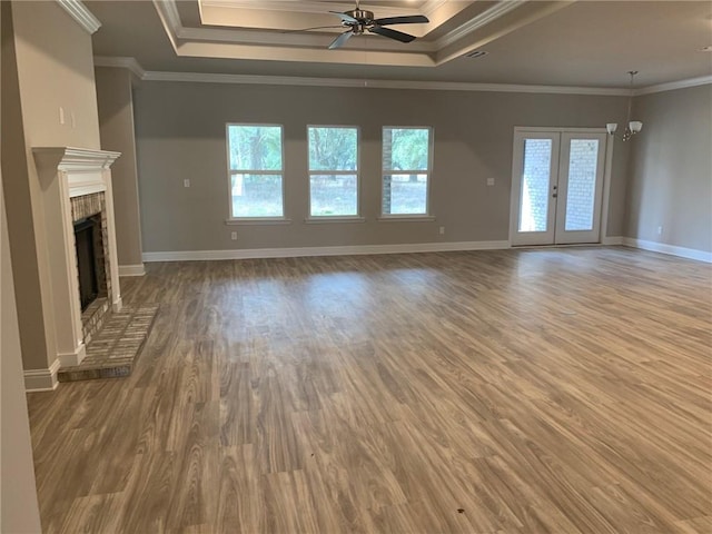 unfurnished living room with a raised ceiling, ceiling fan, wood-type flooring, and ornamental molding