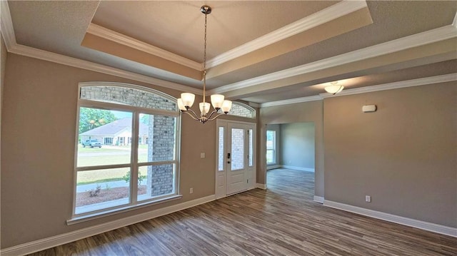 interior space with dark hardwood / wood-style floors, a raised ceiling, ornamental molding, and a chandelier