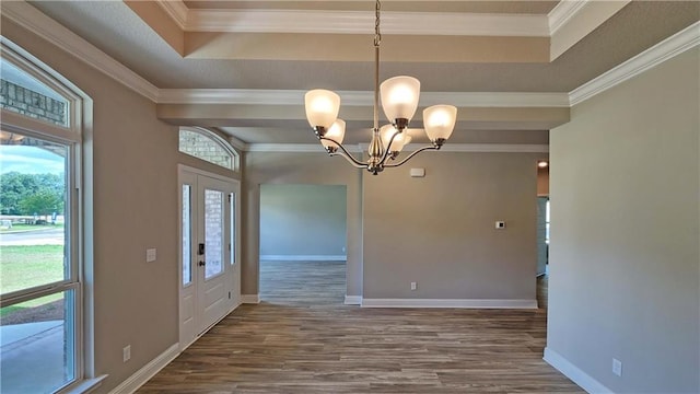 unfurnished dining area featuring a raised ceiling, hardwood / wood-style flooring, ornamental molding, and a notable chandelier