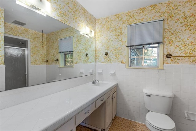 bathroom with toilet, wallpapered walls, and wainscoting