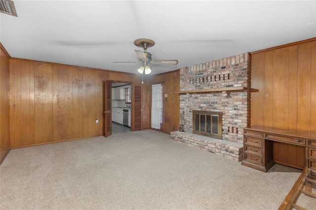 unfurnished living room with carpet floors, visible vents, a fireplace, and wood walls