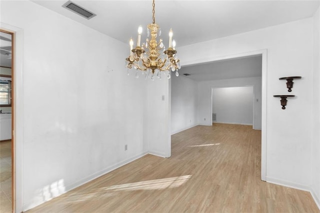 unfurnished dining area featuring a chandelier, wood finished floors, visible vents, and baseboards