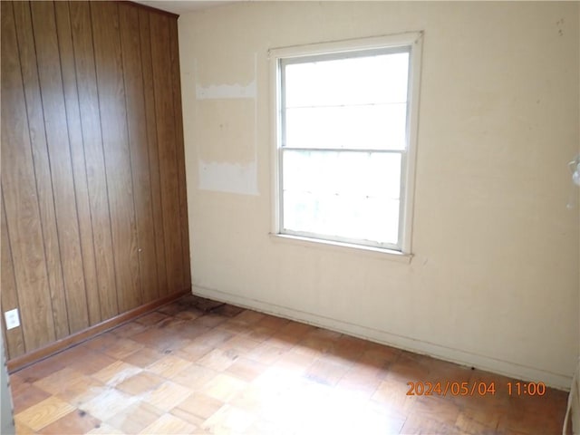 unfurnished room with a healthy amount of sunlight and wooden walls