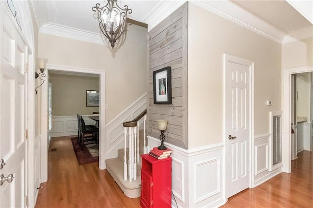 1509 Ridgeland Rd E, Mobile, AL 36695 - staircase with crown molding, a decorative wall, a chandelier, wood finished floors, and a wainscoted wall
