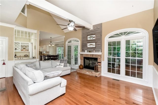 1509 Ridgeland Rd E, Mobile, AL 36695 - living room with light wood-type flooring, a ceiling fan, a chandelier, a large fireplace, and wainscoting