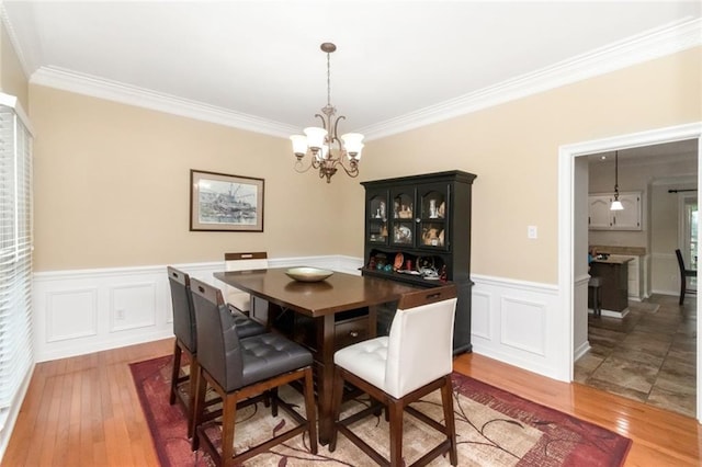 1509 Ridgeland Rd E, Mobile, AL 36695 - dining space featuring a chandelier, ornamental molding, wood finished floors, wainscoting, and a decorative wall