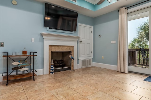 living area with a tile fireplace, visible vents, baseboards, and light tile patterned floors