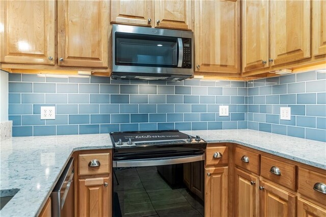 kitchen featuring tile patterned flooring, decorative backsplash, range, light stone countertops, and stainless steel microwave