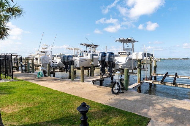 dock area featuring a water view, boat lift, and a yard